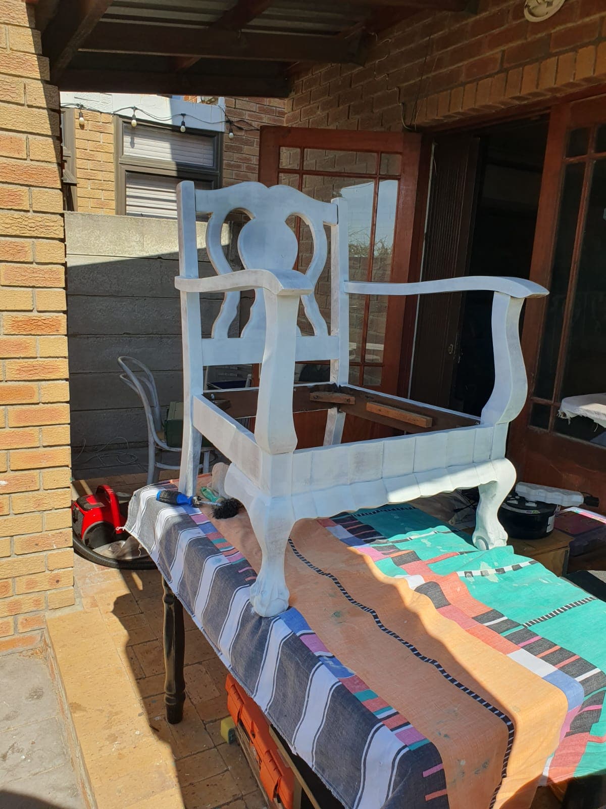 One of the teak armchairs before restoration, in its previous baby-blue painted finish and without a seat cushion