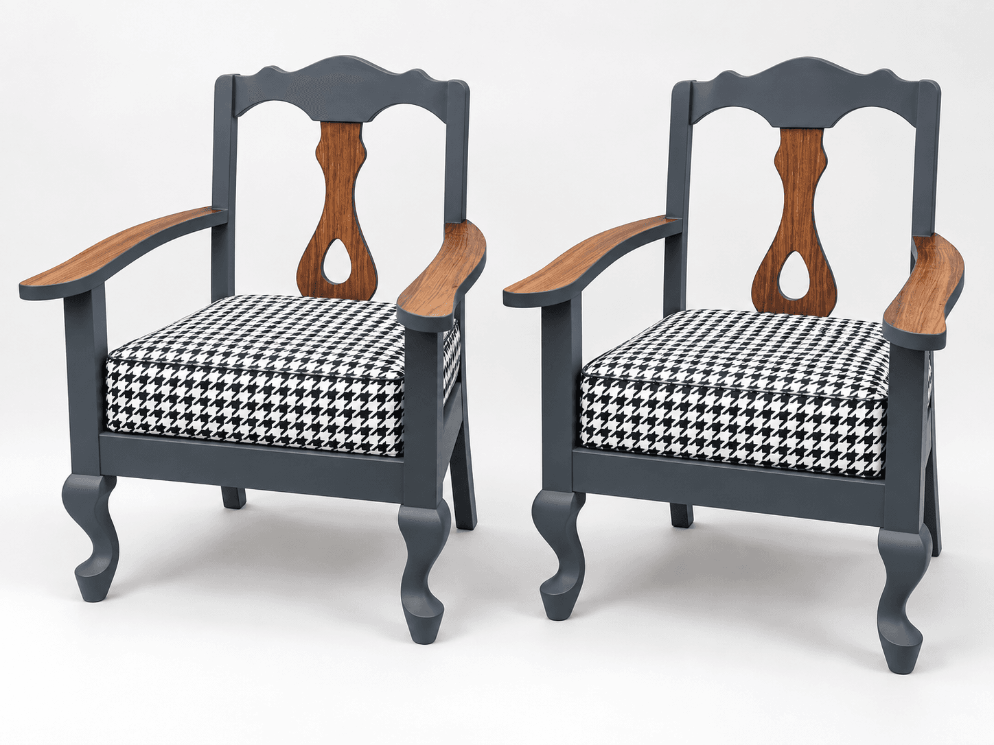 Pair of restored solid teak armchairs with matt grey frames, exposed teak arms and central back splats, and houndstooth tweed cushions, shown in a styled studio presentation